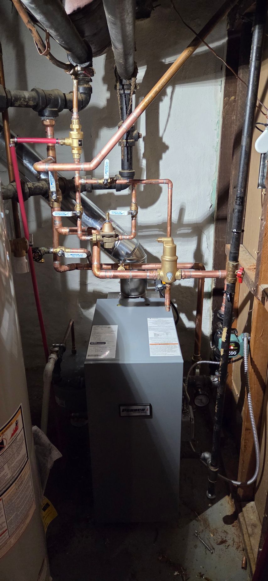 Narrow utility closet with gray furnace, exposed copper pipes, and electrical wiring.