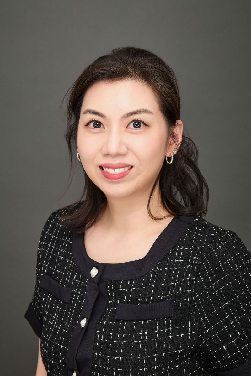 A woman in a black dress is smiling for the camera.