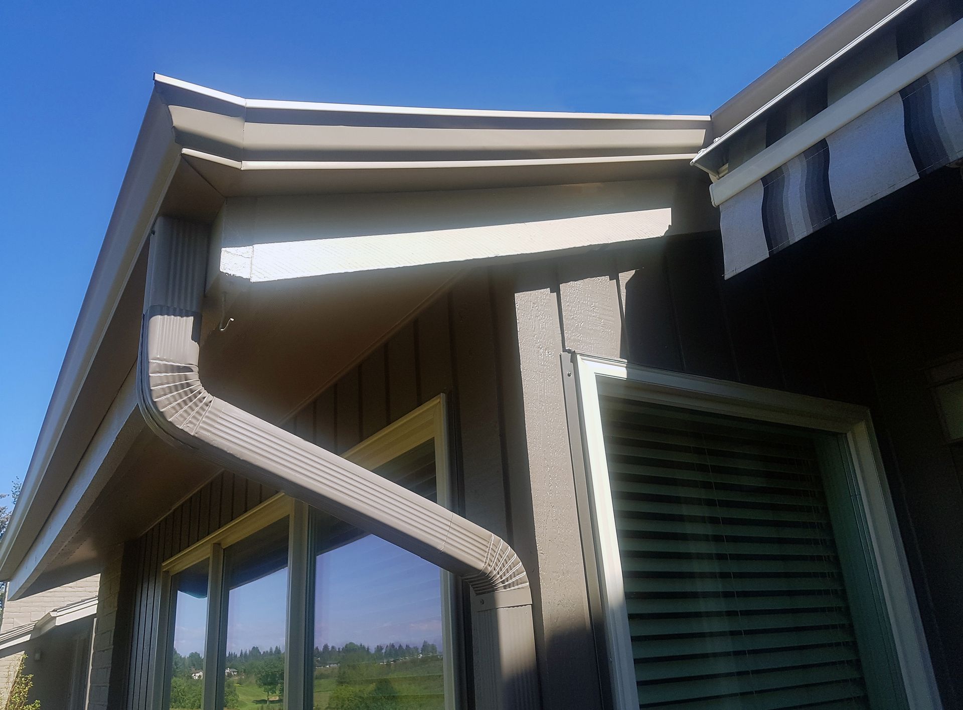 Brown gutters and siding on a building with a blue sky background.