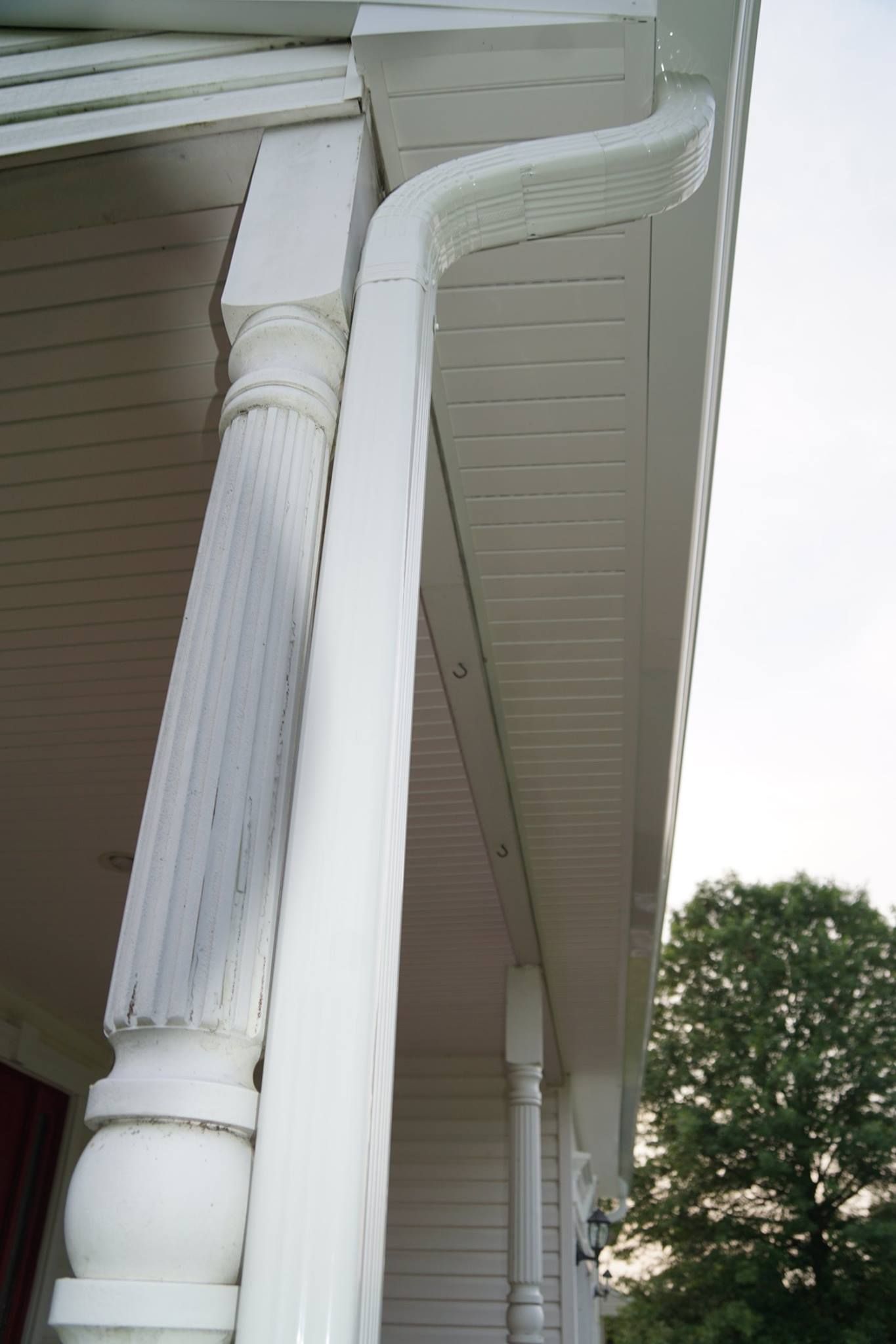 White porch column and gutter against the siding of a building.
