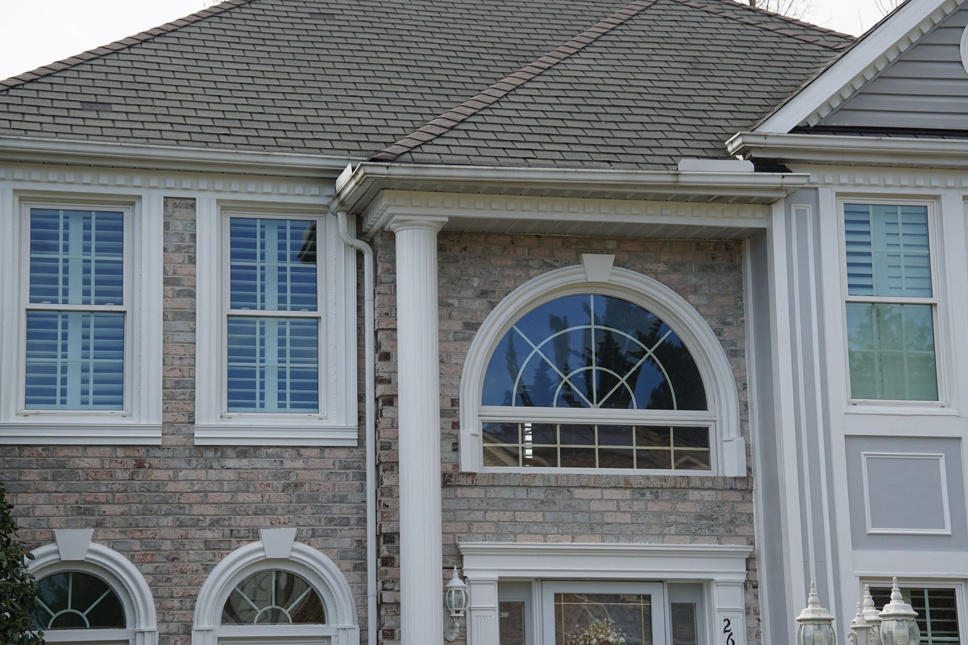 Gray brick house with shutters and an arched window.