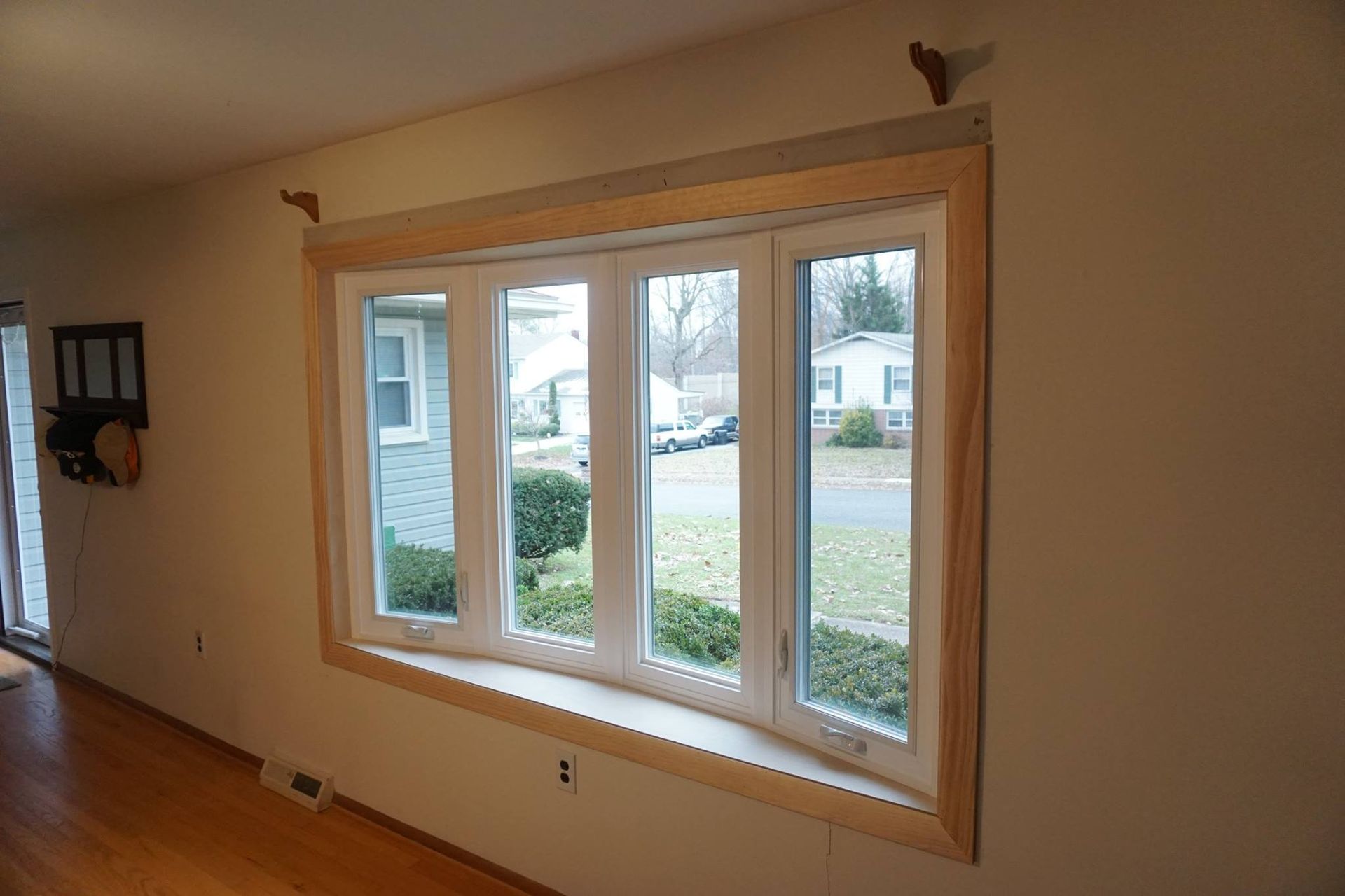 Bay window with light wooden trim. View of outdoors. Interior room.