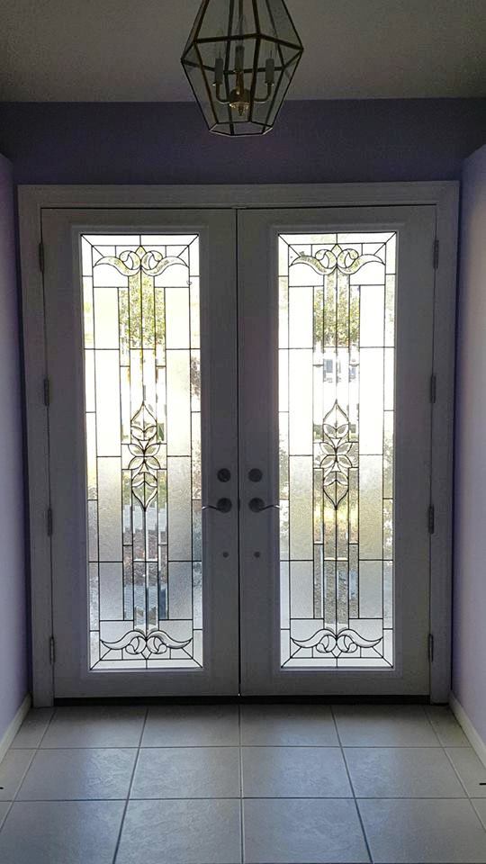 A hallway with stained glass doors and a chandelier hanging from the ceiling.