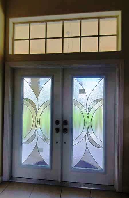 A pair of stained glass doors with a window above them in a room.
