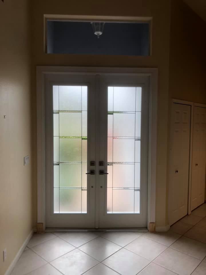 An empty room with a stained glass door and a window.