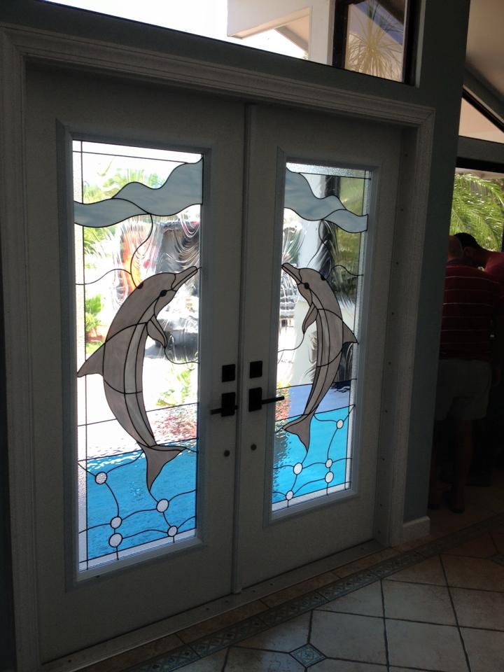 A stained glass door with two dolphins on it