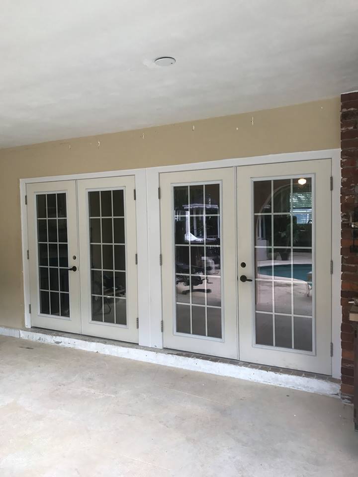 A patio with french doors and a pool in the background