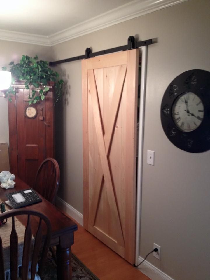 A sliding barn door in a room with a clock on the wall