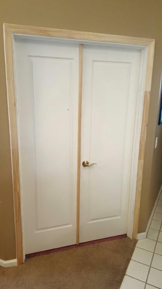 A pair of white double doors with wooden trim in a hallway.