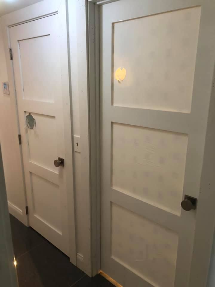 A hallway with two white doors and a black floor