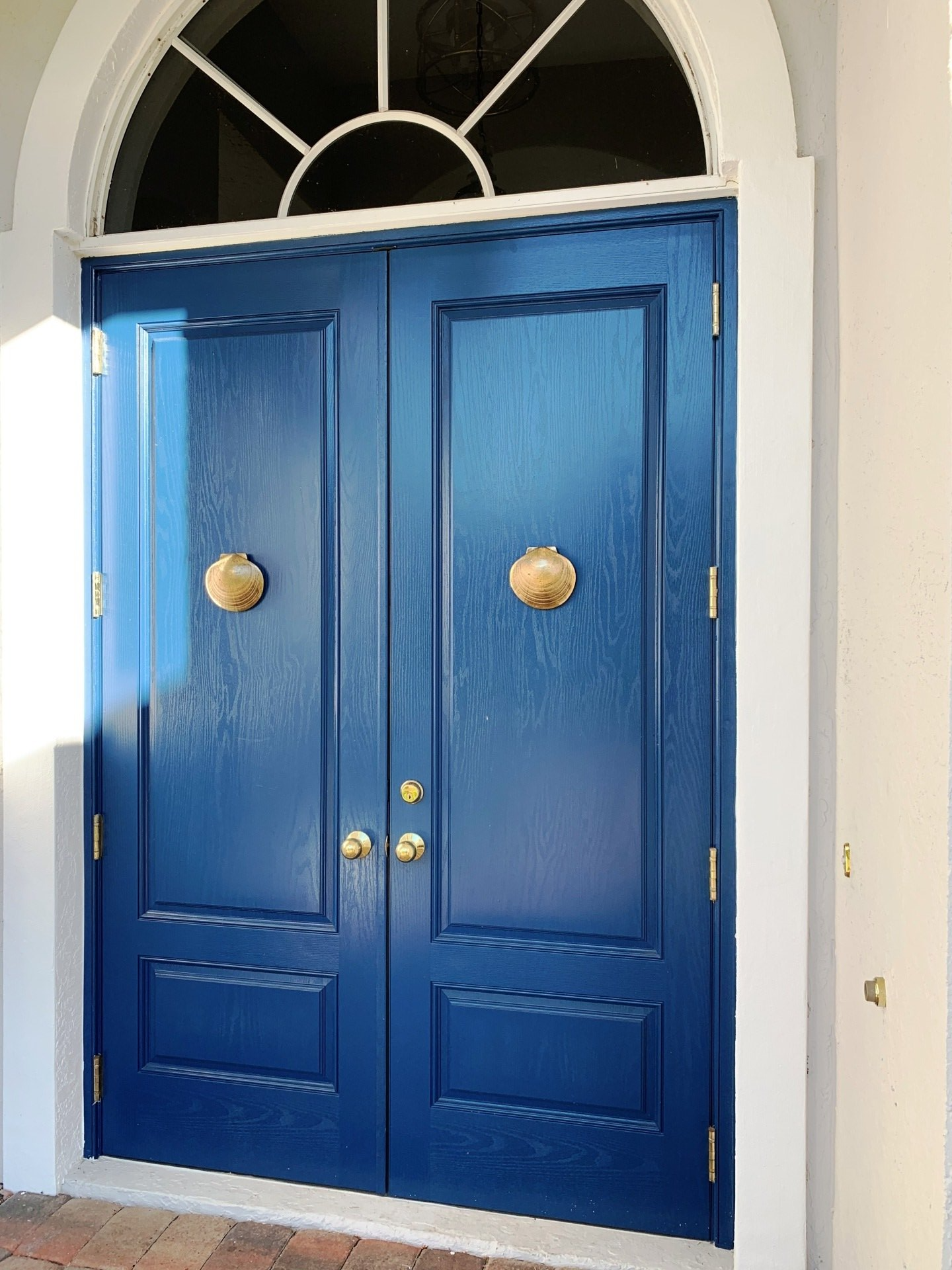 A pair of blue doors with gold handles and a white frame.