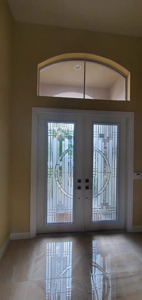 An empty room with a stained glass door and a window.