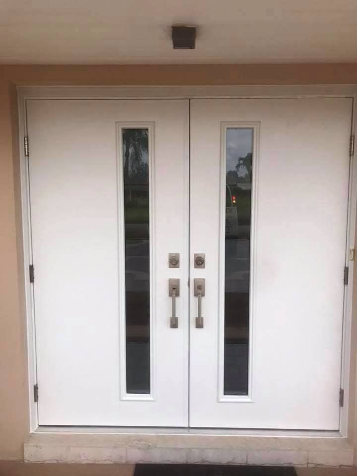 A pair of white double doors with glass windows on a beige wall.