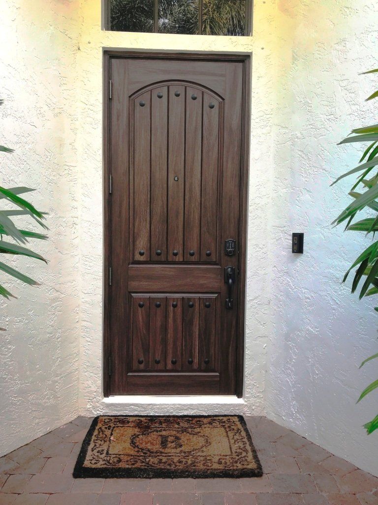 A wooden door with a welcome mat in front of it.