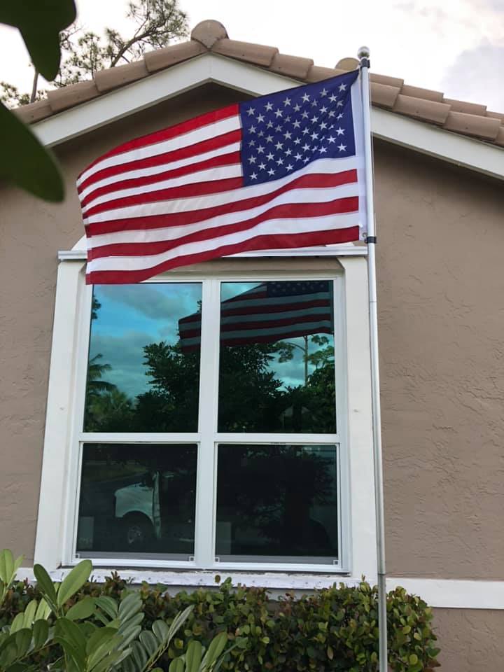 An american flag is flying in front of a window of a house.