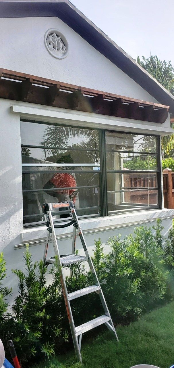 A ladder is sitting in front of a house with a large window.