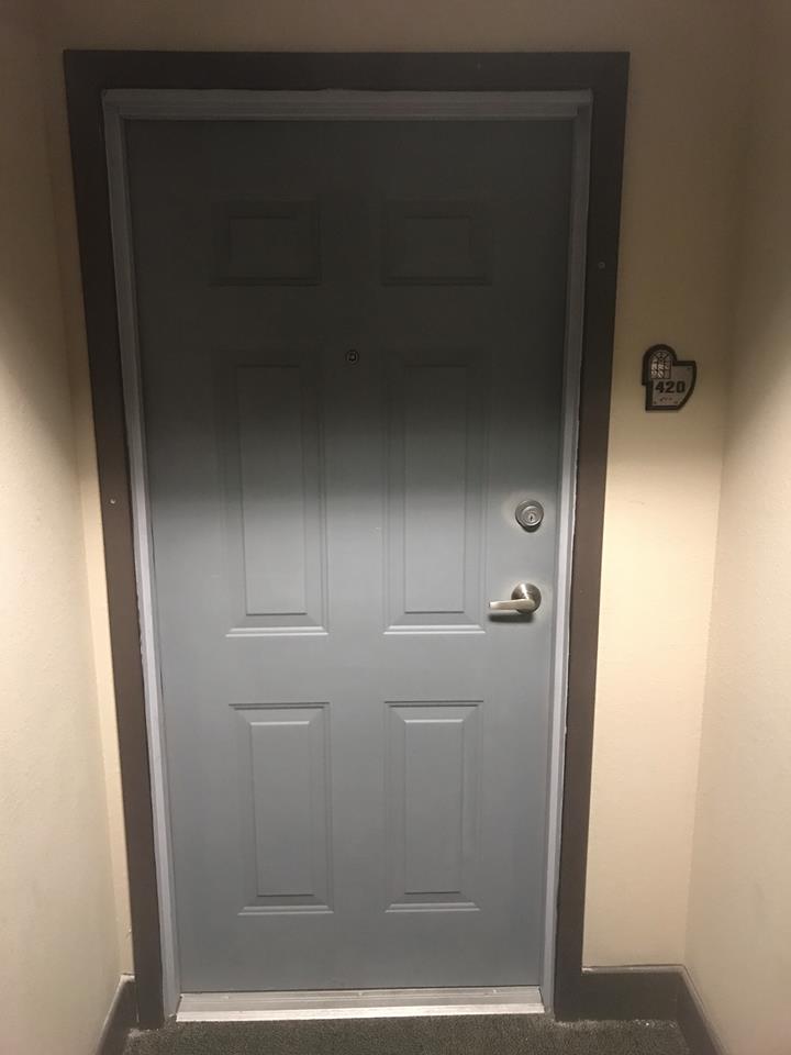 A gray door with a heart on the wall next to it.