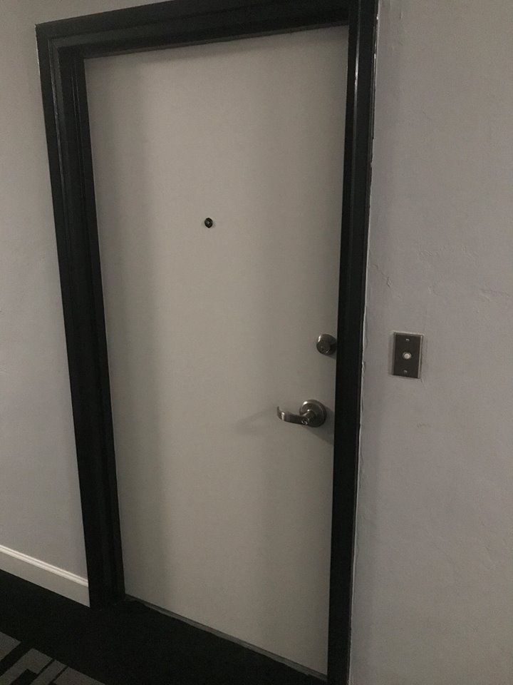 A white door with a black frame and handle in a hallway.