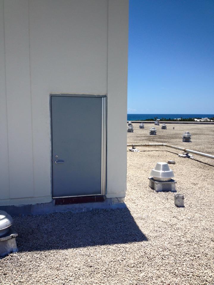 A door on the side of a building with a view of the ocean.