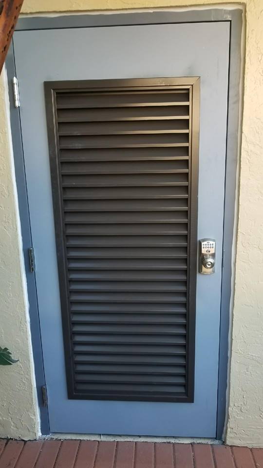 A door with shutters on it is on a brick wall.