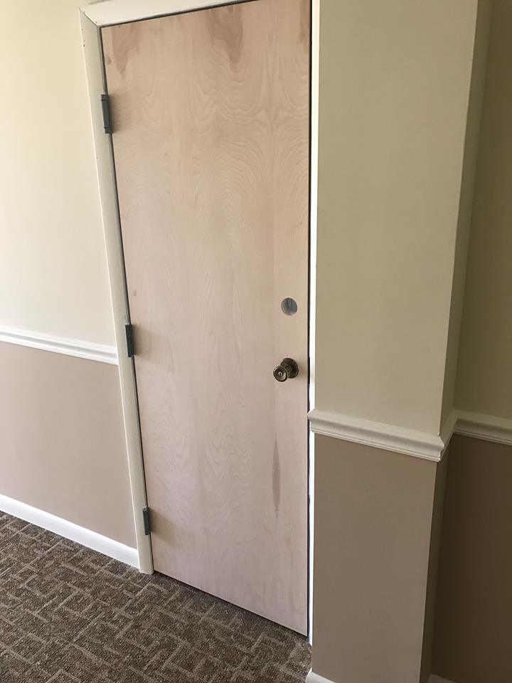 A wooden door is sitting in a hallway next to a wall.