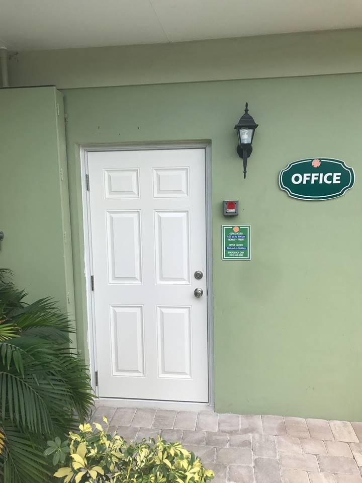 A green building with a white door and a sign that says office.