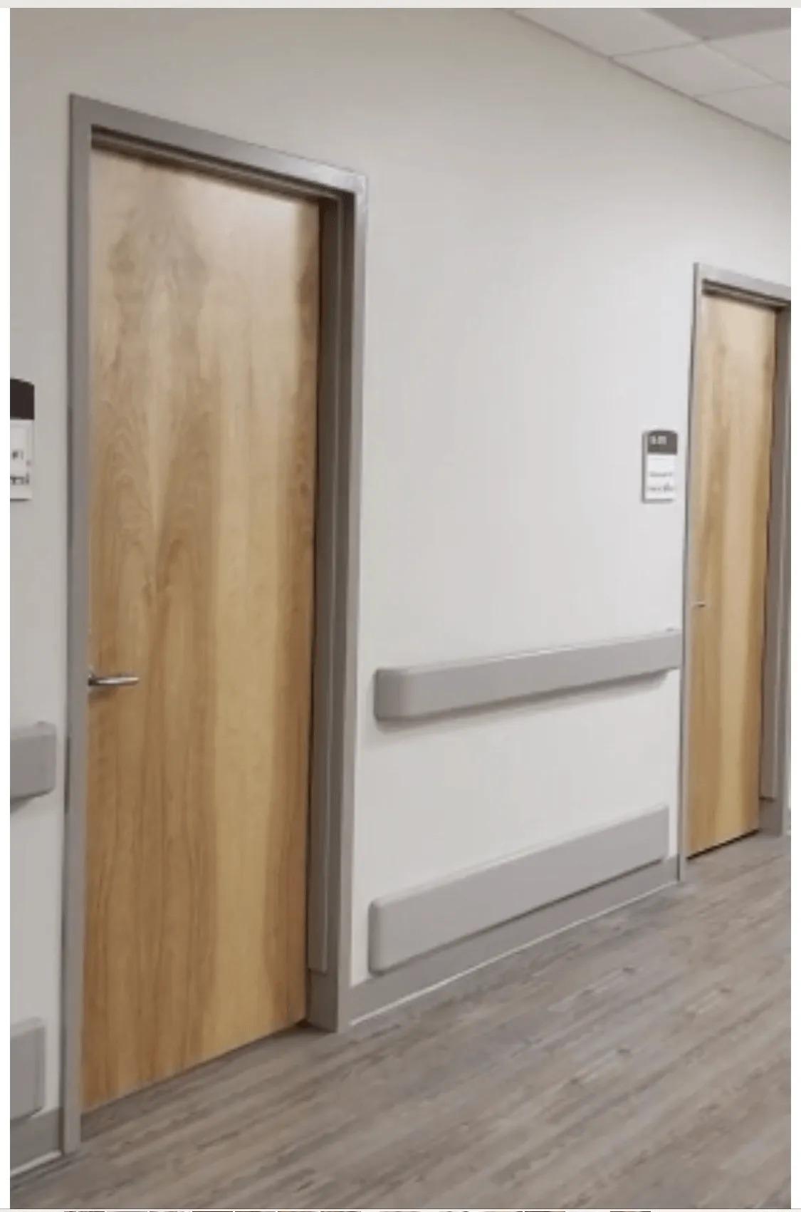 A hallway with two wooden doors and a white wall.