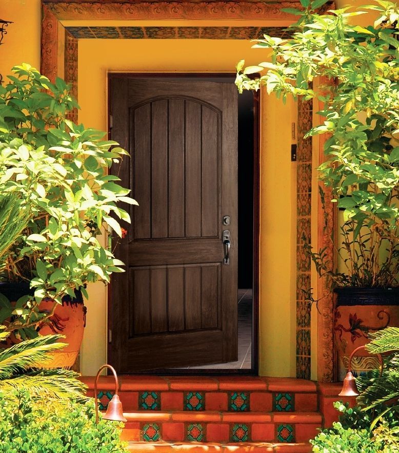 A wooden door is open to a yellow house