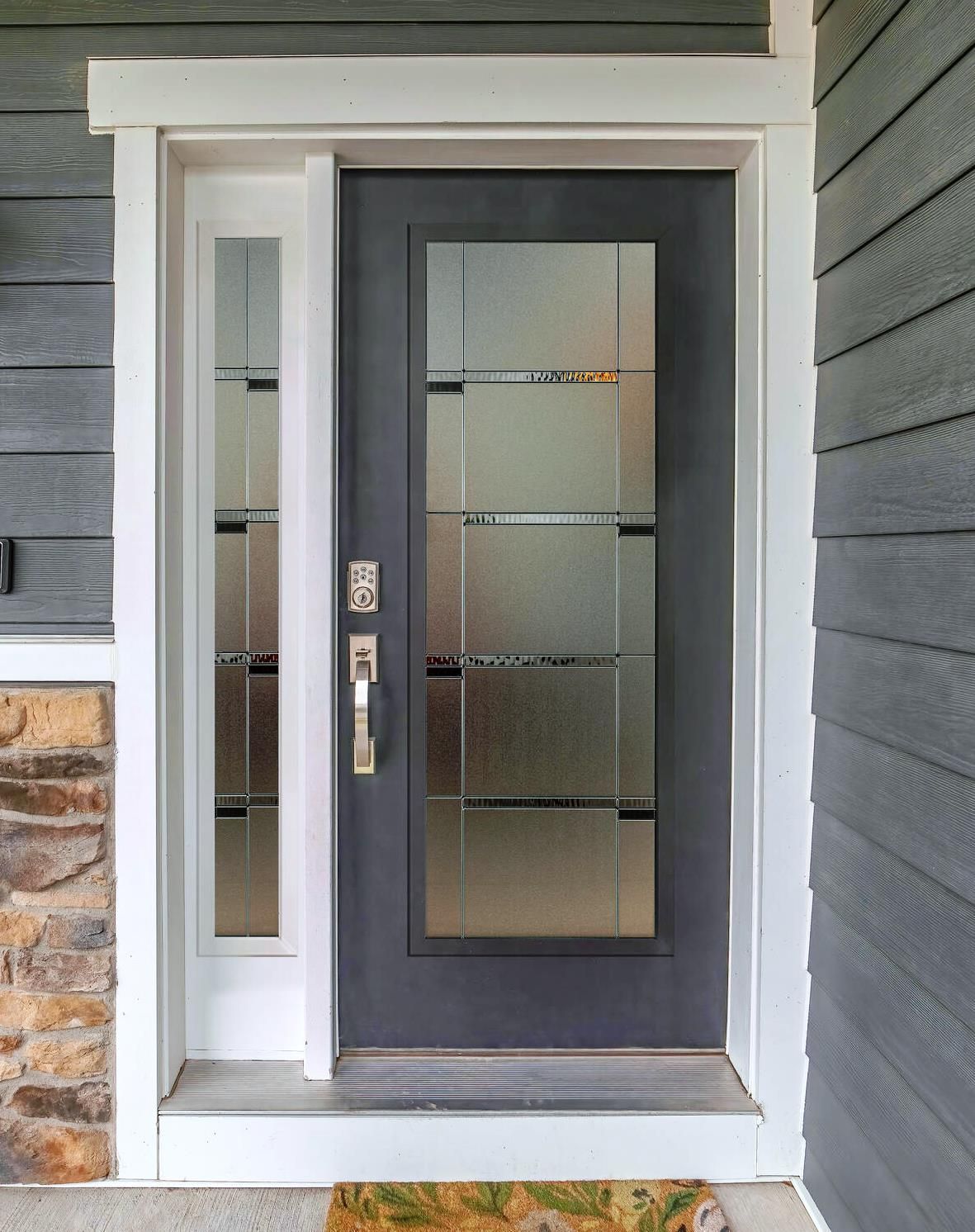 The front door of a house with a gray siding and a white trim