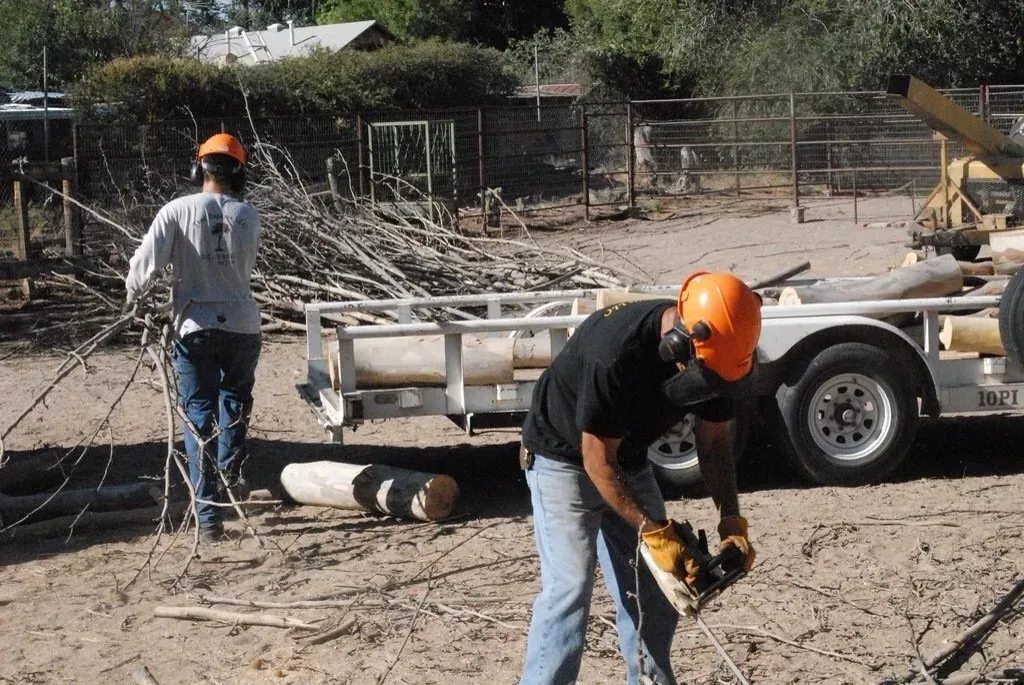 Two men wearing hard hats are working in a dirt field