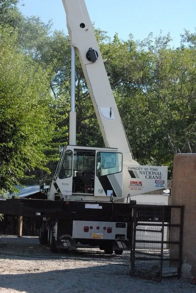 A large white crane is parked in a gravel lot