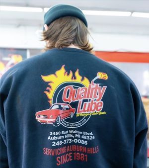 Person wearing a navy Quality Lube shirt with shop logo and contact details on the back