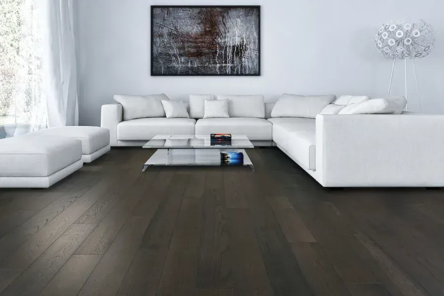 Modern white living room with sectional sofa, dark wood floor, coffee table, and wall art