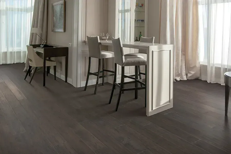 Modern dining area with white chairs and table beside large curtains, on dark wood flooring