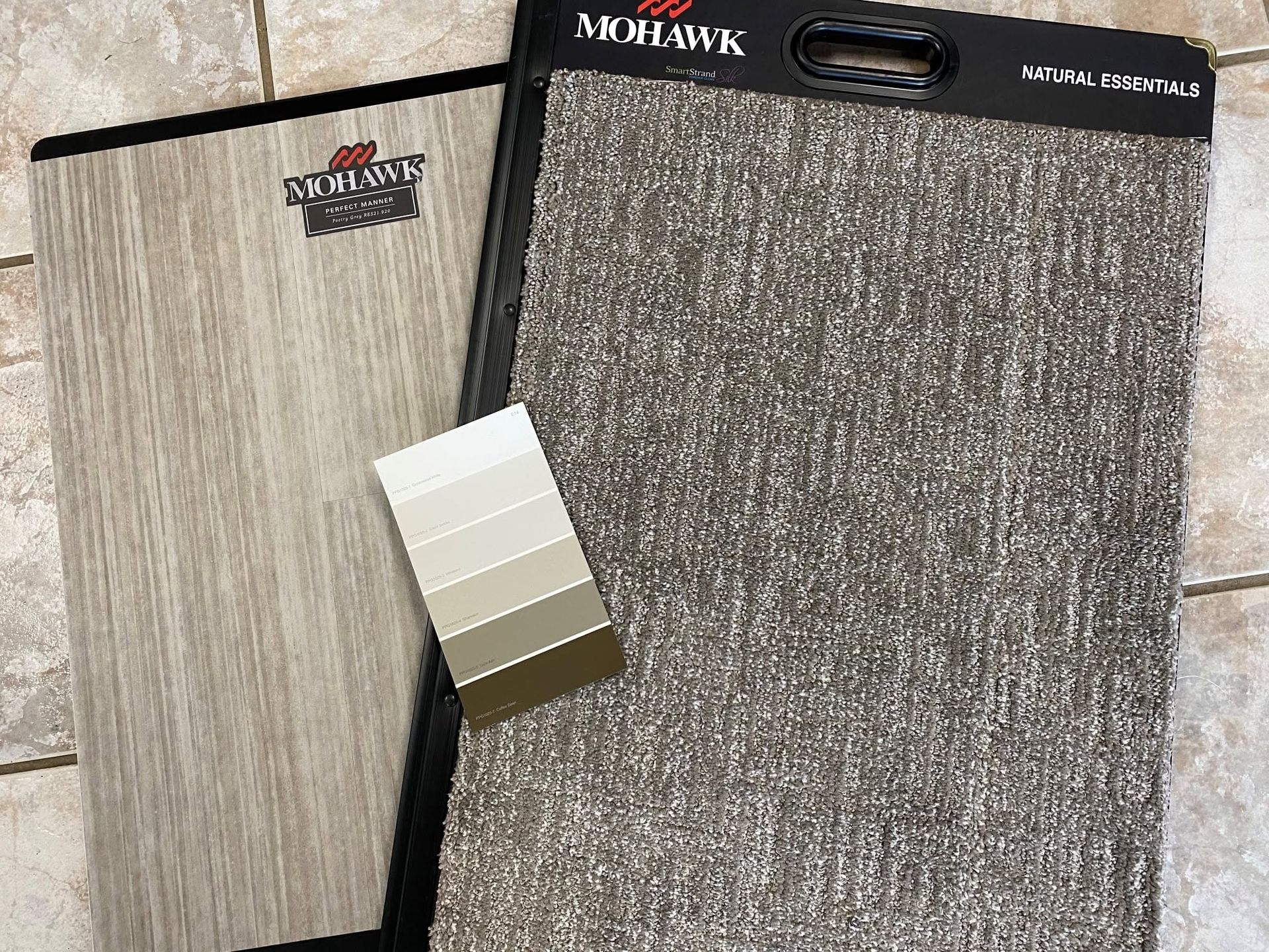 Two Mohawk flooring sample boards, one beige woodgrain and one dark gray textured, shown side by side.