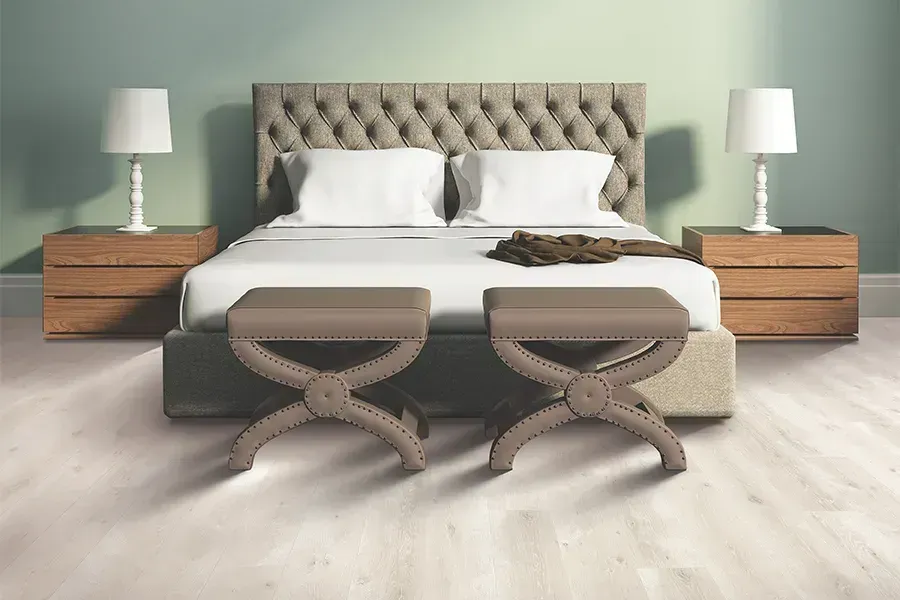 Modern bedroom with tufted bed, white bedding, wooden nightstands, lamps, and two upholstered benches.