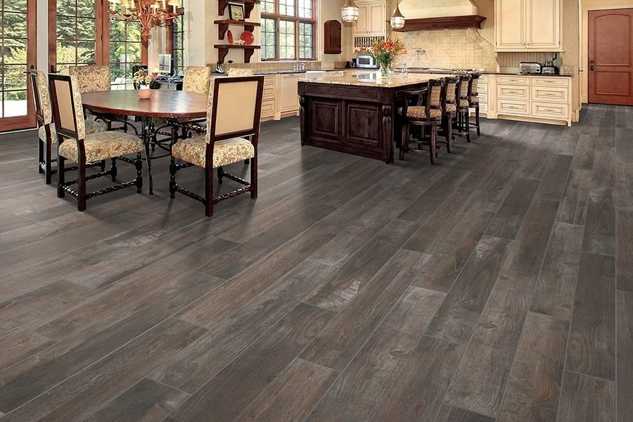 Modern dining room with dark wood floors, a large table, chairs, and an island kitchen in the background
