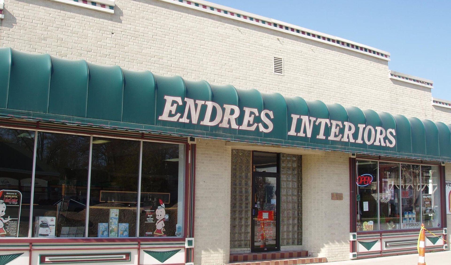 Storefront with green awning reading &ldquo;ENDRES INTERIORS&rdquo; on a brick building.