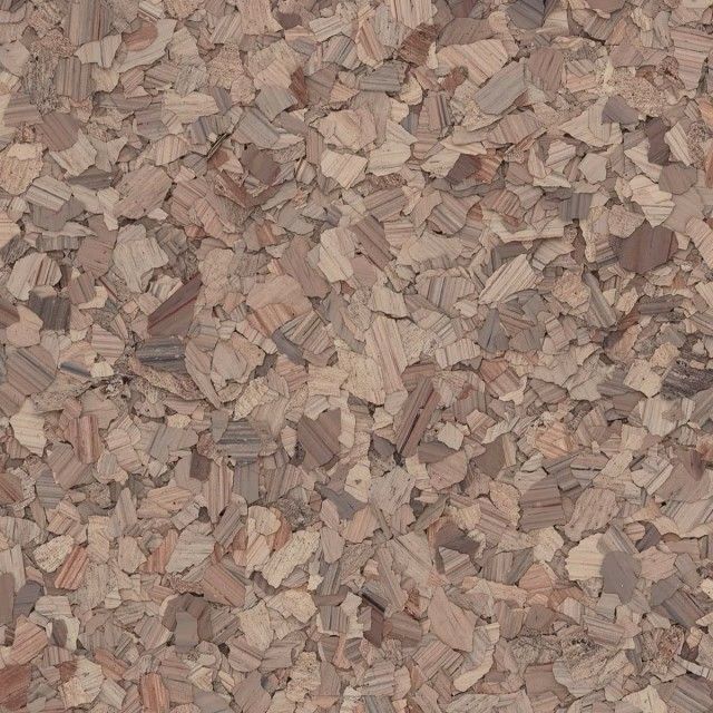 A close-up of a textured surface featuring a mix of small, tan and brown wood-like shavings or cork particles.