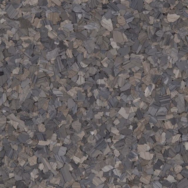 A close-up texture of multi-tonal gray and beige vinyl paint chips used for garage or industrial floor coatings.