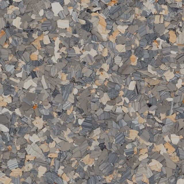 A close-up texture of decorative vinyl floor flakes in shades of grey, white, and tan.