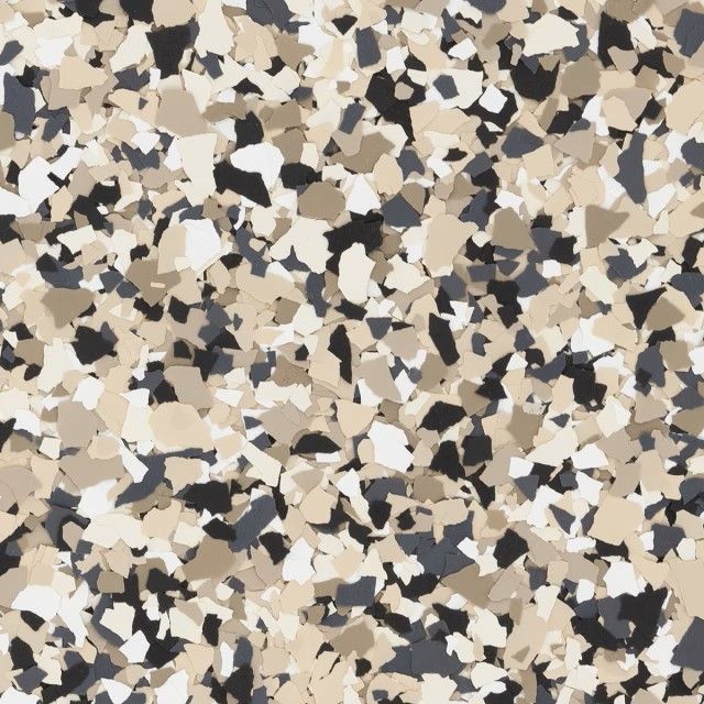 A close-up of decorative epoxy floor flakes in shades of beige, cream, white, charcoal, and black.