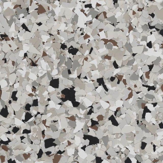 A close-up of decorative epoxy floor flakes in a blend of white, light gray, beige, brown, and black chips.