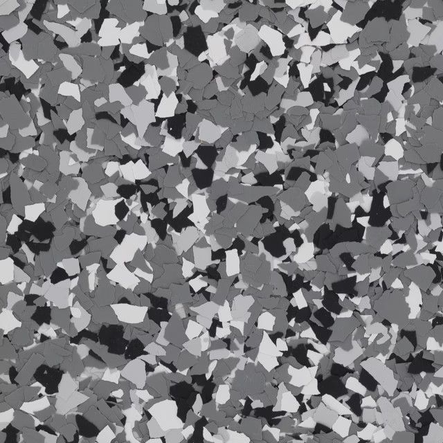 A close-up view of grey, white, and black paint chips or flakes in a speckled pattern, often used for epoxy flooring.