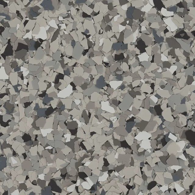 A close-up of multi-sized, decorative vinyl floor flakes in shades of grey, charcoal, and white.