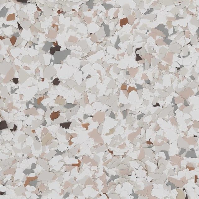 A close-up of decorative epoxy floor flakes in white, beige, brown, and gray.