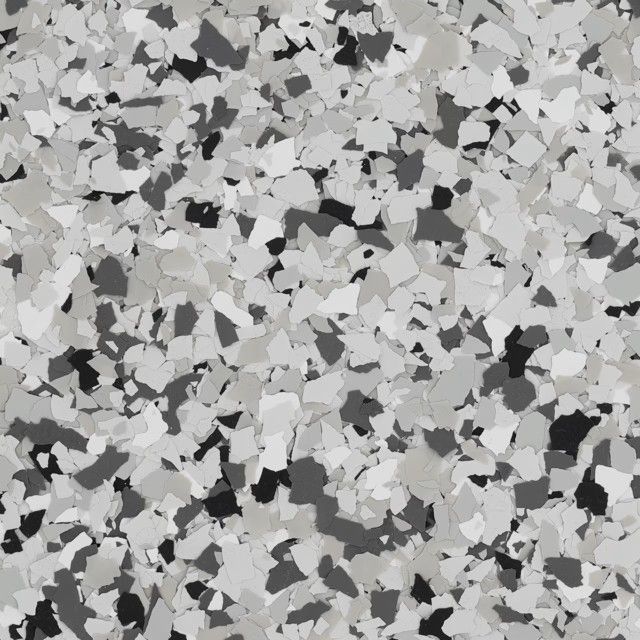 A close-up of monochromatic, multi-sized grey, black, and white decorative floor flakes used in epoxy flooring.