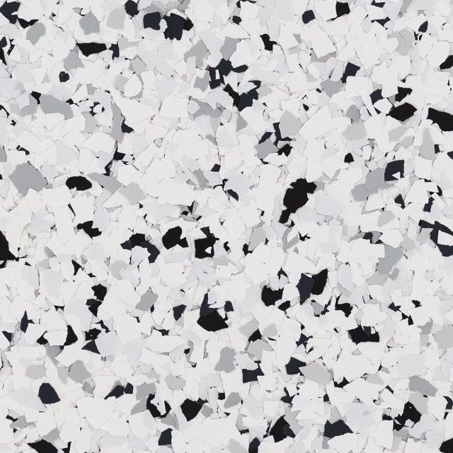 A close-up view of decorative floor flakes in a mix of white, gray, and black chips.