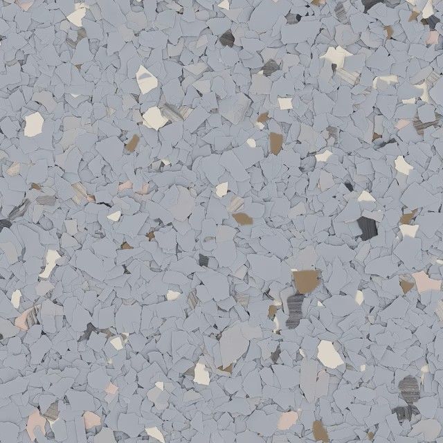 A close-up of grey epoxy garage floor coating with scattered white, light grey, and dark brown paint chips.