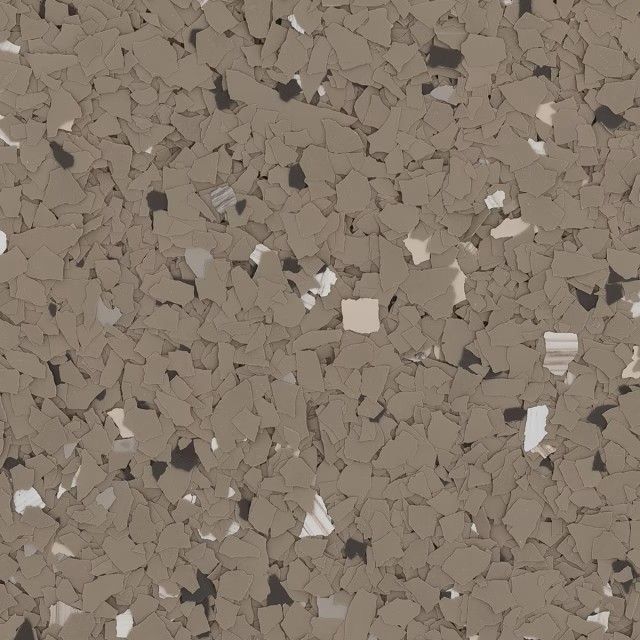 A close-up view of tan epoxy flooring with scattered, multi-sized flakes in shades of brown, white, and black.